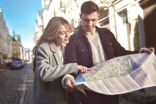 Couple of young tourists reading a map in the city