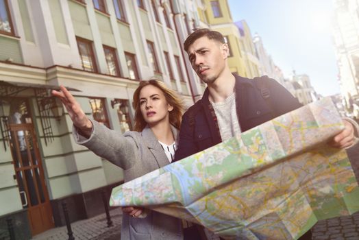 Couple of young tourists reading a map in the city