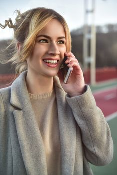 Cute smiling young woman talking on phone standing on the bride. Close up portrait