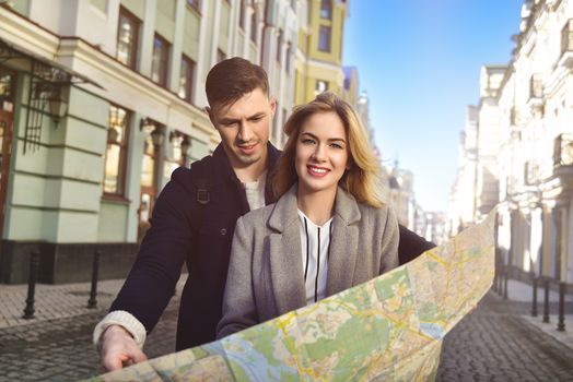 Couple of young tourists reading a map in the city