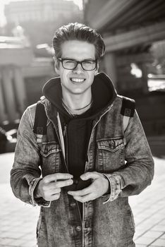 Smiling man with glasses stay at city with a backpack