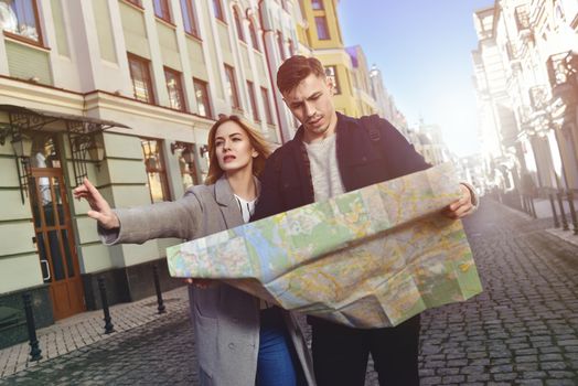 Couple of young tourists reading a map in the city