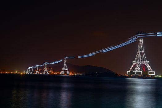 Cable car Eiffel tower night view at illuminated to Vin pearl Amusement Park (Hon Tre Island) Island, cableway long rope road on water bay Nha Trang, Vietnam