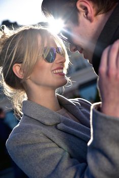 Happy playful couple in sunglasses in love dating joking and laughing in the street