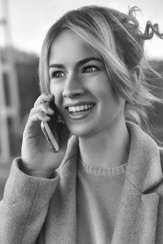 Cute smiling young woman talking on phone standing on the bride. Close up portrait