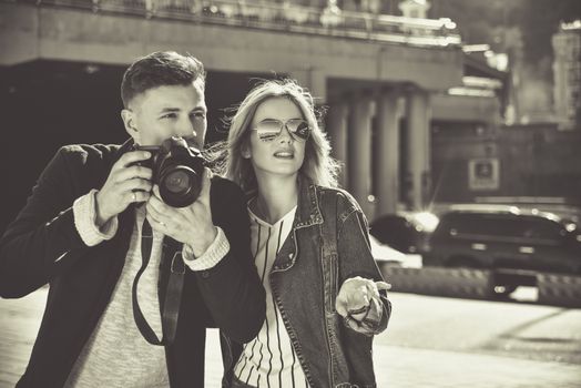 Romantic couple walk at the street with photo camera in BW