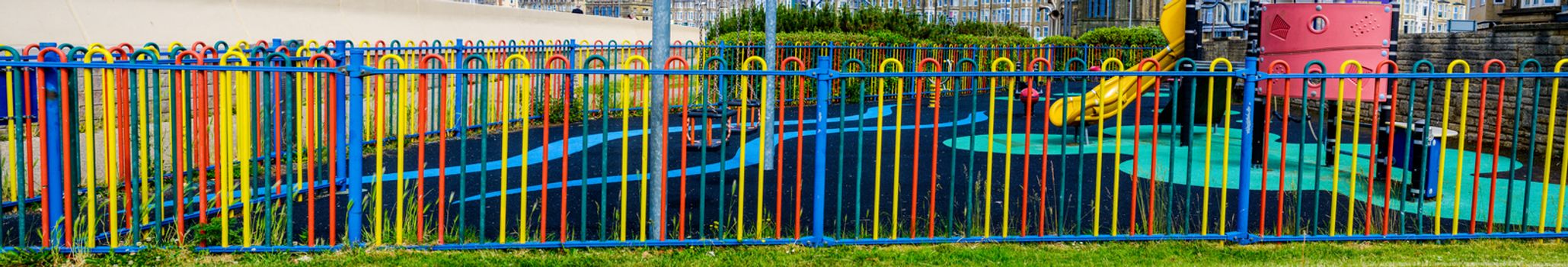 Colorful garden fence with playground int the background