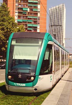 BARCELONA, SPAIN - AUGUST 01, 2102: Tram driving green trees at street of Barcelona. Catalonia, Spain