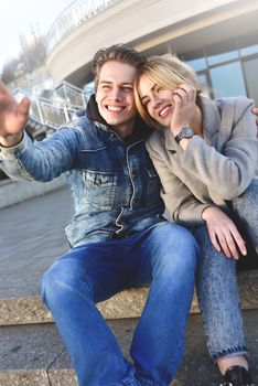 Attractive young couple sitting on floor in urban street and dreaming about something