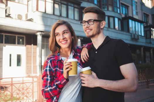 Awesome couple walking at street and drink a coffee