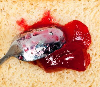 red strawberry marmalade preserves, spread over a slice of white bread