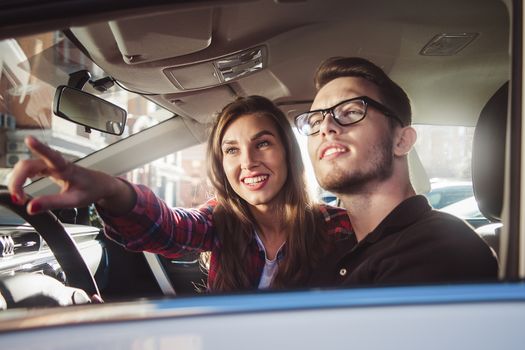 Enjoying travel. Beautiful young couple sitting on the front passenger seats and smiling while handsome man driving a car.