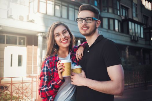 Awesome couple walking at street and drink a coffee