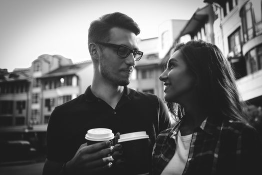 Awesome couple walking at street and drink a coffee