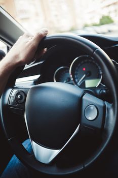 Male arms holding leathern rudder of car