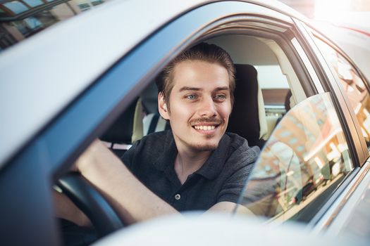 Enjoy the drive. Image of young handsome guy sitting in car.