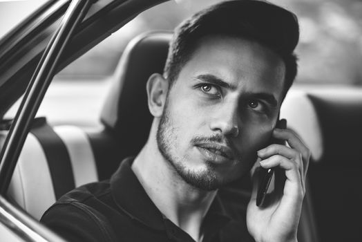 Handsome man sit in the back seat of the car and use a phone.