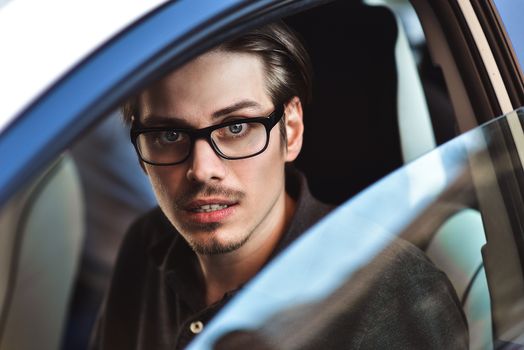 Enjoy the drive. Image of young handsome guy sitting in car.