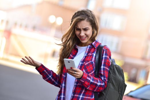 Young girl talking on the phone in the street surfing on the phone