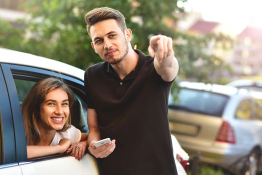 Beautiful girl sitting in the car and flirting with guy who outdoor standing