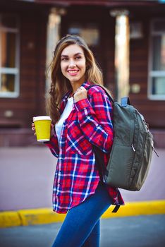 Beautiful girl walking on the street with coffee.