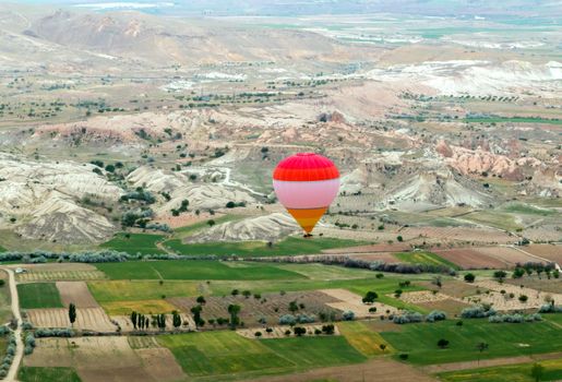 Hot air balloon flying over rock landscape, attraction of Cappadocia is an air flight. village location, Turkey, Asia.