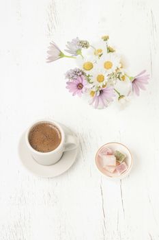 Cup of coffee and Turkish delight on a wooden table with colorful spring flowers on