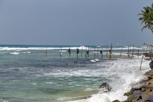 Local traditional stilt fishermen fishing rod in Indian ocean, Sri Lanka.