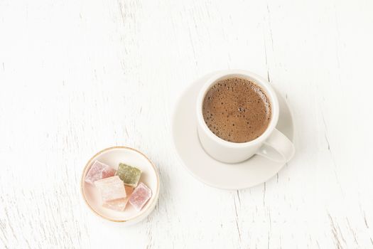 Cup of coffee and colorful Turkish delights on a wooden table with copy space