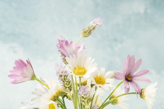 colorful bouquet of spring flowers against soft blue background with copy space