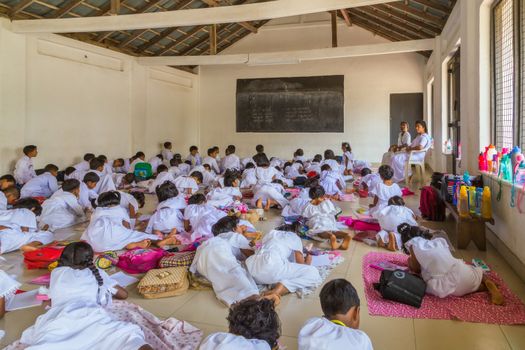KANDY, SRI LANKA - JANUARY 31, 2016: Lesson in school Sri lankan teacher writes on the blackboard, Tutoress teaches Young girls and boys, children in classroom at lesson.