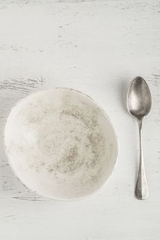an empty and clean ceramic bowl and spoon on a table with copy space