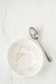 an empty and clean ceramic bowl and spoon on a table with copy space
