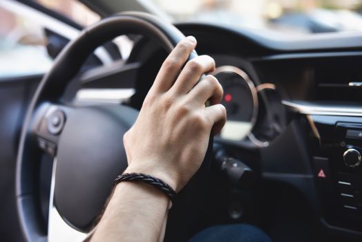 Man arms holding rudder in automobile, sunny day