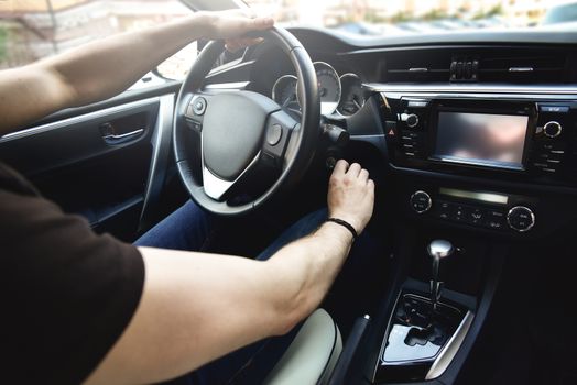 Male arms holding leathern rudder of car