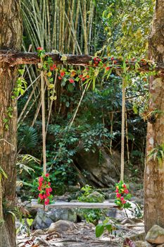 Wedding pergola seesaw lonely swing decorated with flowers at garden