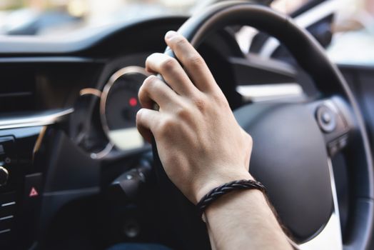 Man arms holding rudder in automobile, sunny day