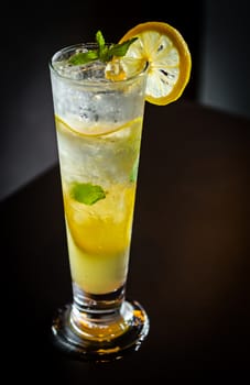 Mojito cocktail with lime and mint in high glass on wooden table.