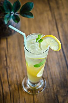 Mojito cocktail with lime and mint in high glass on wooden table.