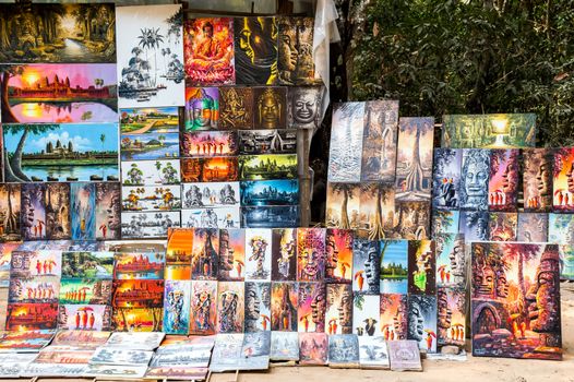 SIEM REAP, CAMBODIA - 01 MARCH, 2015 - Tourists market for paintings drawing pictures of Angkor Wat, Cambodia, Khmer temple complex, Asia. Ancient Khmer architecture in jungle.
