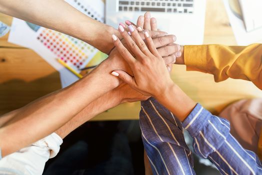 Close up top view of young business people putting their hands together.