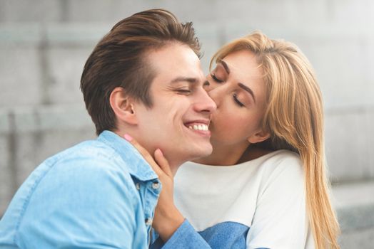 Happy to spending time together. Young beautiful couple outdoor fashion portrait. Attractive boy and girl hugging and kissing.