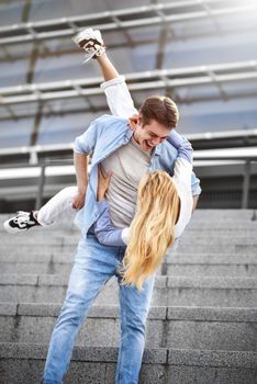 Man giving his pretty girlfriend a piggy back at street smiling at each other on a sunny day.