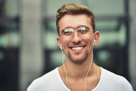 People, technology, travel and tourism - man with earphones, smartphone on city street and listening to music over gray wall background