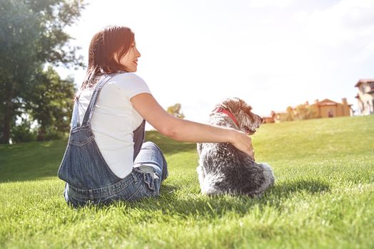 Pretty adult caucasian happy woman resting in the park on a sunny day with her beloved dog. happy caucasian woman hugs her beloved dog. love animals