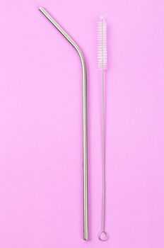 reusable stainless steel straws and cleaning brush on pink background, eco friendly lifestyle