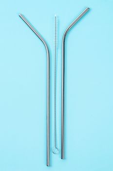 reusable stainless steel straws and cleaning brush on blue background, eco friendly lifestyle