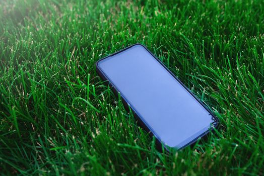 Smartphone and black screen on grass background