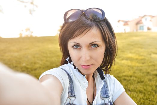 Adult caucasian woman n nature, taking selfie and walking in the evening park . selfie