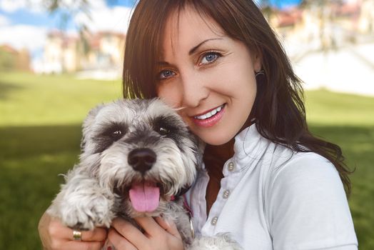 Portrait of a happy caucasian woman who hugs her beloved dog.The concept of love for animals. best friends. Dog breed Schnauzer. sunny day